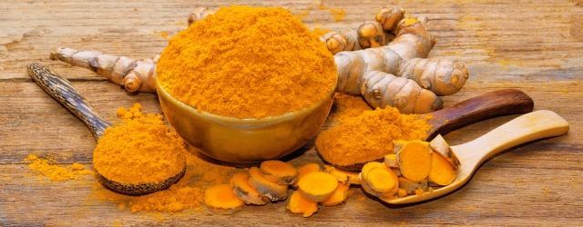 fresh turmeric roots on wooden table